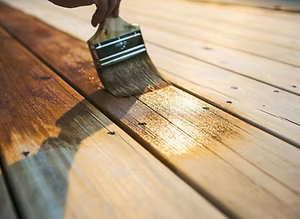 Person applying wood finish to a wooden surface with a brush