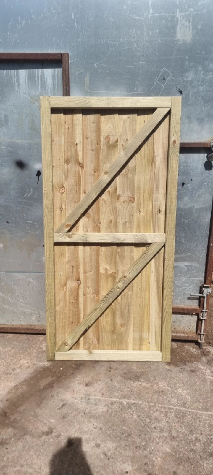 Wooden gate with a geometric design on a concrete floor and metal wall background